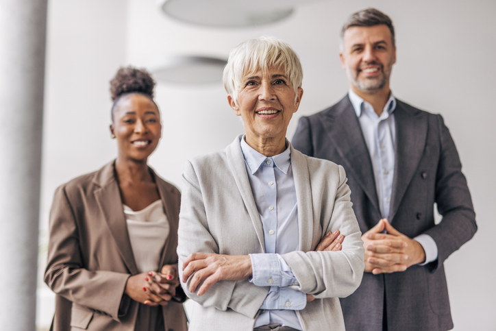 Three private wealth advisers in a modern glass office building discussing an Indexed Universal Life policy illustration